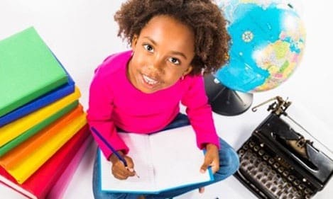 a young girl writing in an open notebook